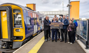 Small group of people including SENRUG Chair Dennis Fancett standing on the platform at Newsham station next to a train, and holding a sign saying 2 million passengers